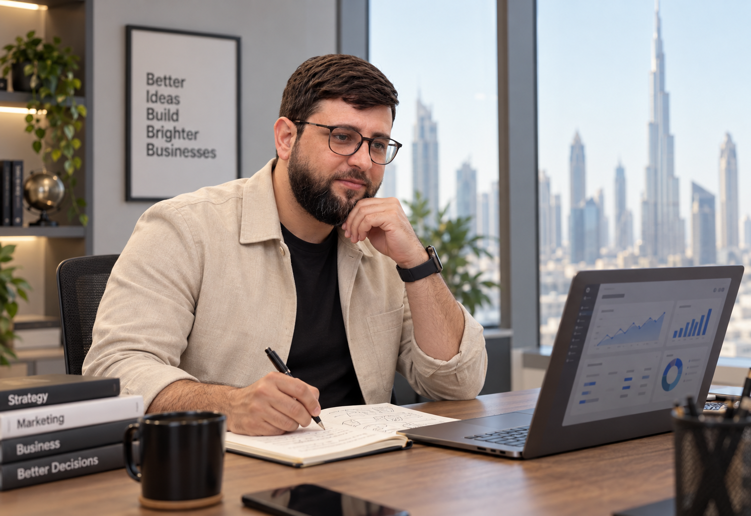 Muhammad Ali Abbasi seated at a desk with a notebook, laptop and Dubai skyline